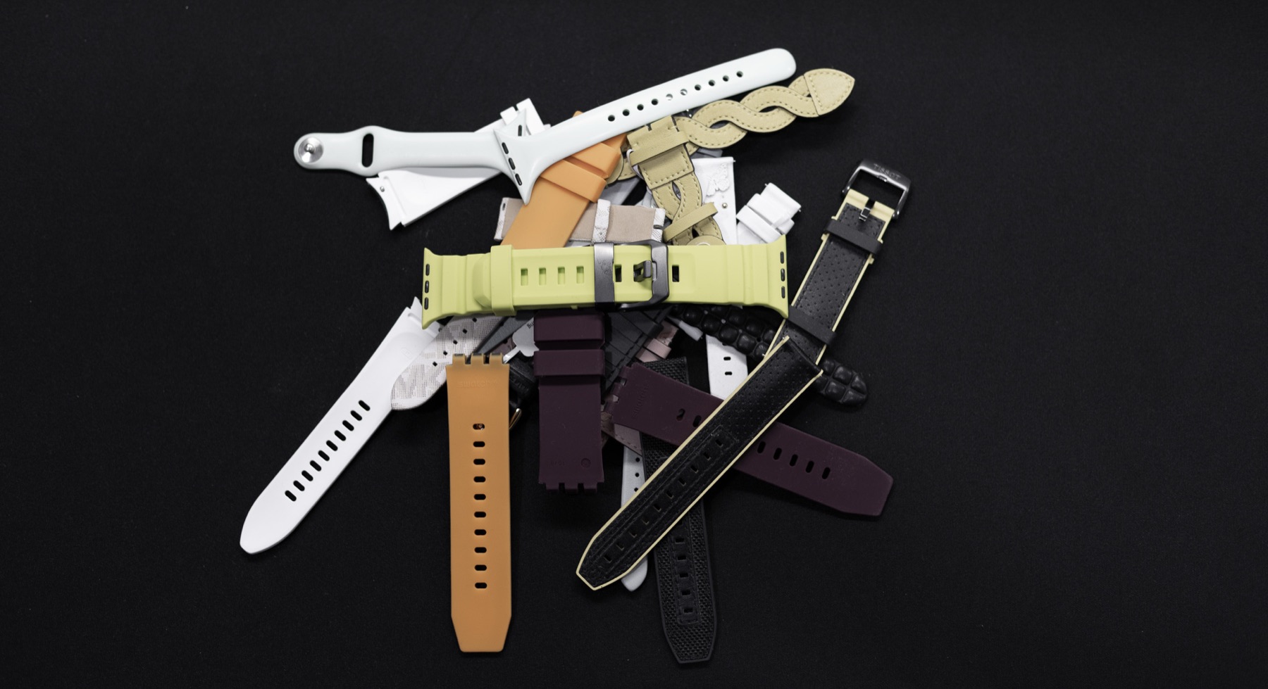 A pile of used sport bands, silicone straps, and leather straps.